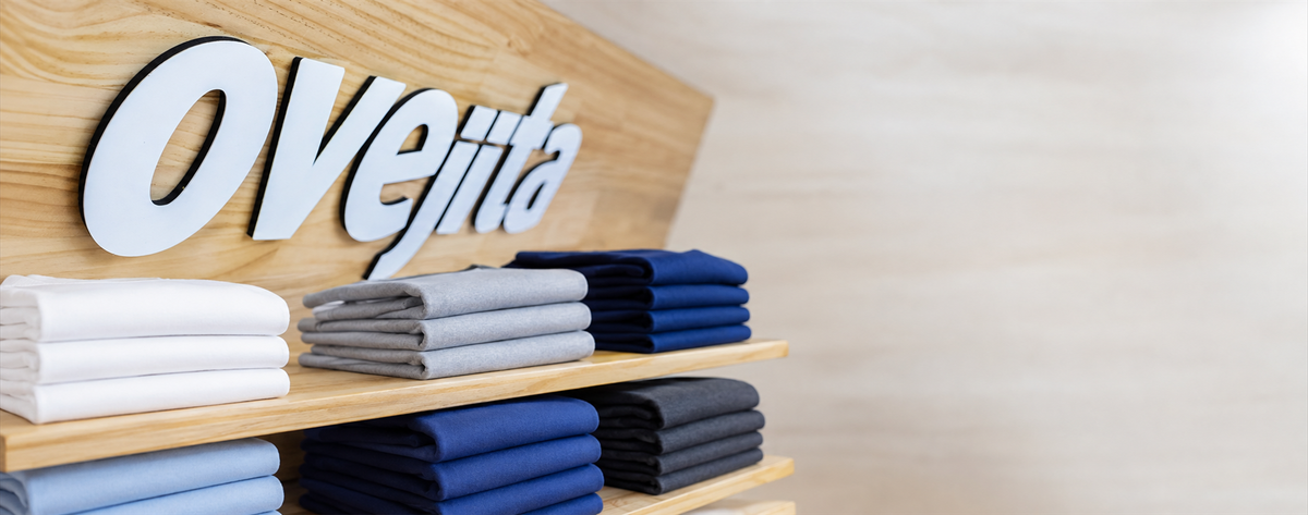 Interior de tienda Ovejita con letrero sobre madera y franelas de algodón unicolor