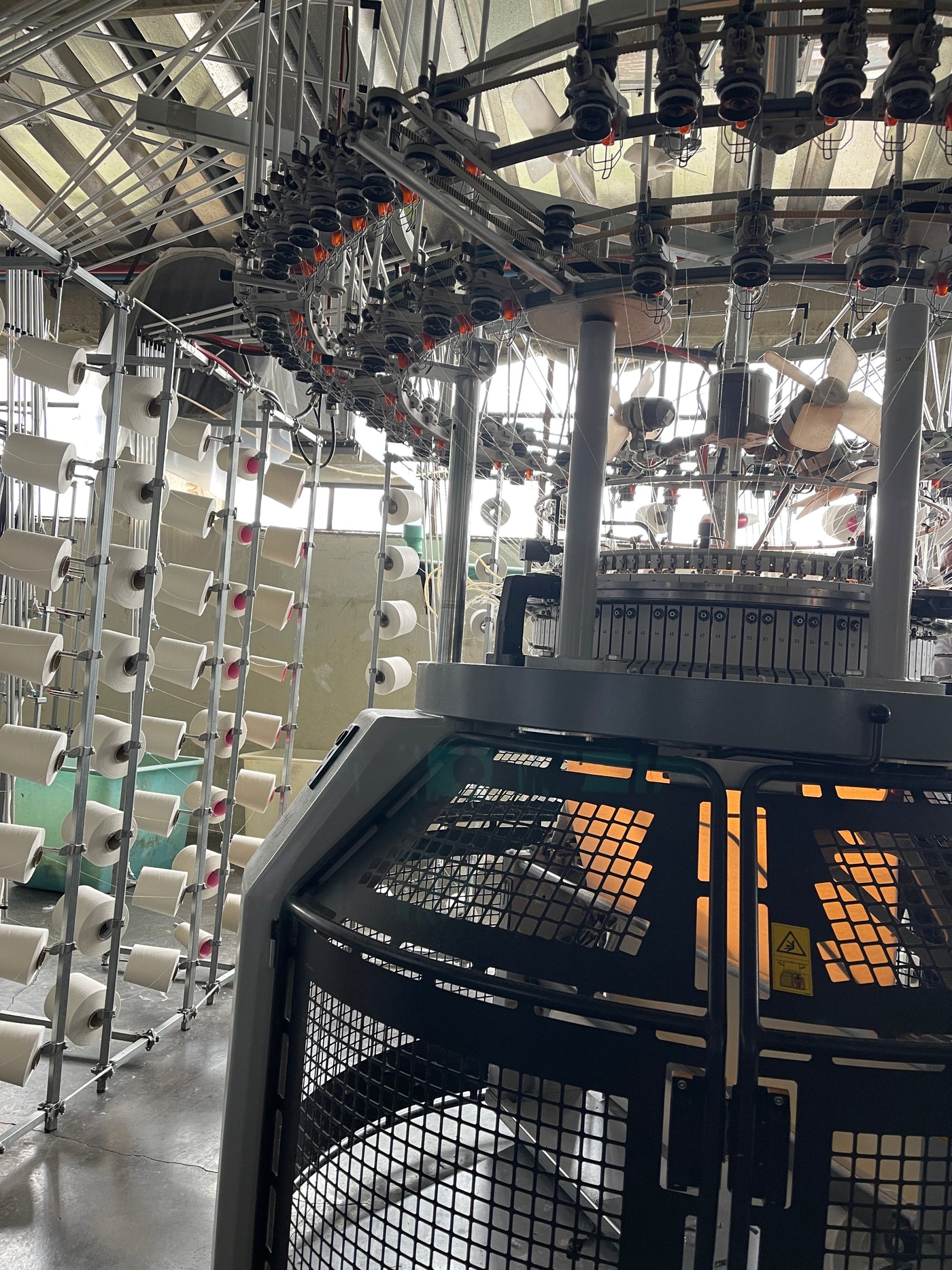 Máquina de tejeduría y conos de hilo en una planta Ovejita. Fotografía de 2022.